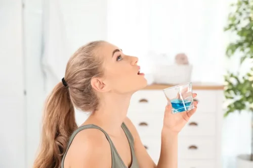 Kvinde bruger mundskyl til at rense tungen