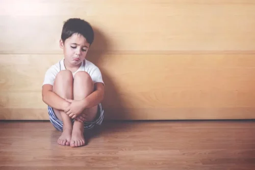 Trist dreng sidder på gulv
