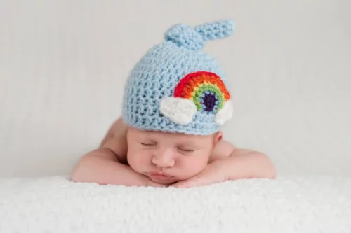 Baby med regnbue på huen symboliserer regnbuebørn