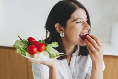 Kvinde spiser salat, der består af regulerende fødevarer