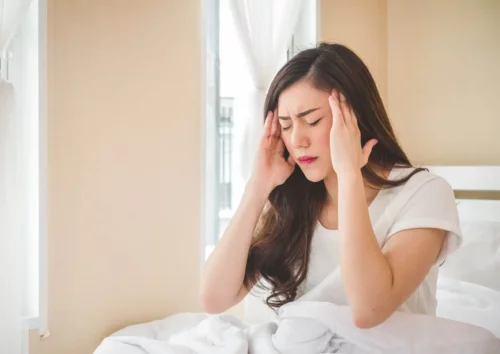 Kvinde i seng har hovedpine