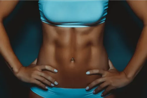Kvinde viser en meget muskuløs mave frem