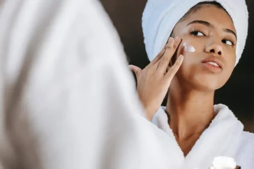 Kvinde påfører ansigtscreme som en del af at passe på huden om efteråret