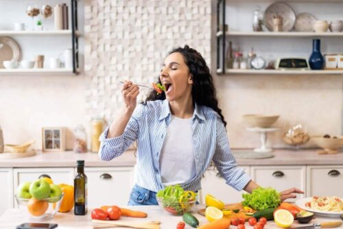 Kvinde spiser salat i sit køkken