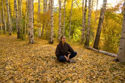 Kvinde mediterer i skov og anvender Shinrin Yoku