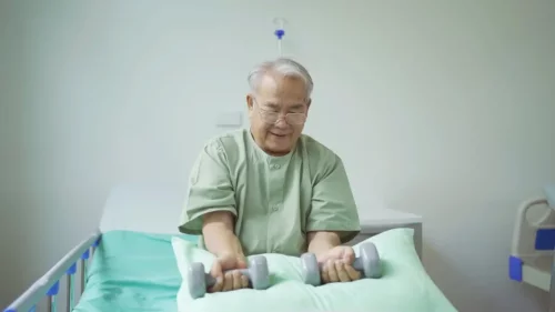 Mand laver aktiveringsøvelser for sengeliggende
