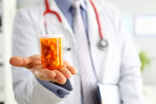 Læge holder et glas med piller