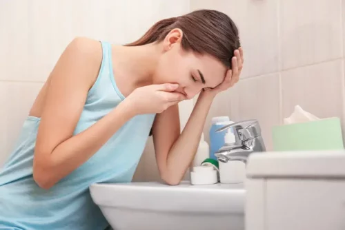 Kvinde med kvalme sidder ved toilet