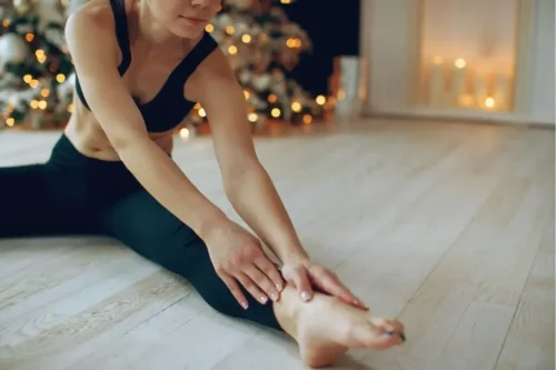 Kvinde motionerer foran juletræ, da julen er en kardiovaskulær risikofaktor