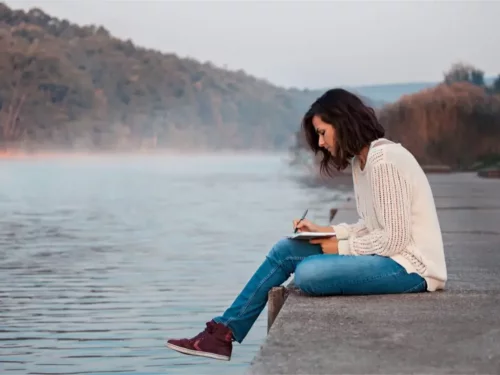 Kvinde skriver dagbog ved en sø