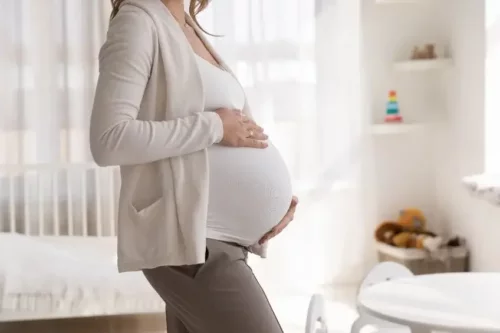 Gravid kvinde står på badeværelse