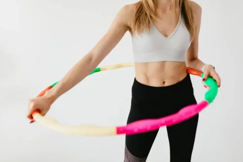 Kvinde viser, hvordan man træner med hulahopringe med vægt
