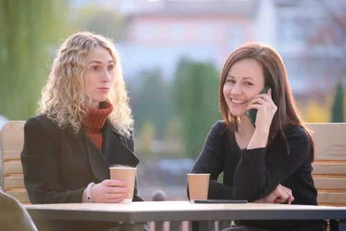 En kvinde ignoreres af en anden kvinde, der taler i telefon