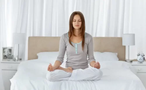 Kvinde mediterer i seng