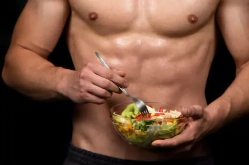 En muskuløs mand spiser salat og udnytter proteinsyntese