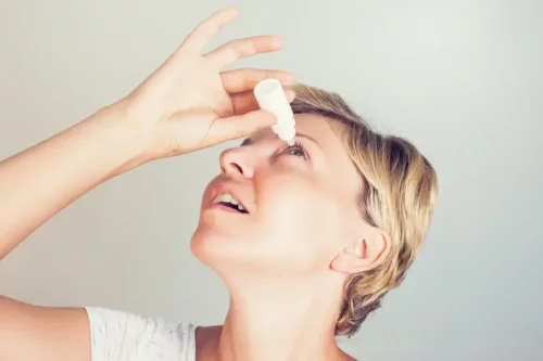 Kvinde bruger øjendråber til at behandle tics ved øjet