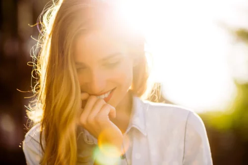 Smilende kvinde med solen bag sig