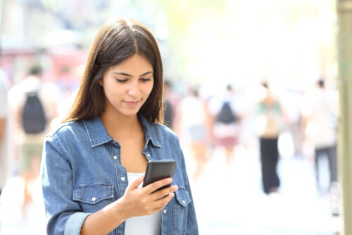 Smilende kvinde ser på telefon