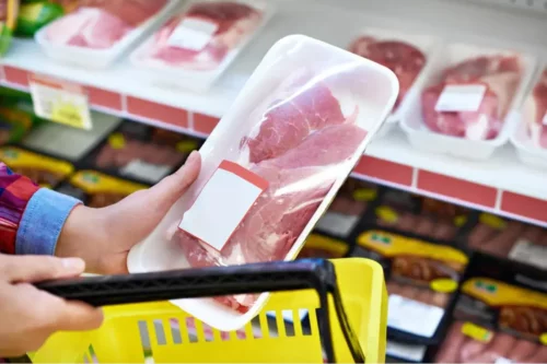 En person tager kød i et supermarked