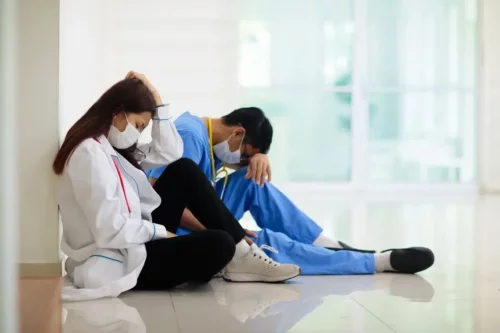 Sundhedspersonale sidder på gulv og skildrer udbrændthedssyndrom hos sundhedspersonale