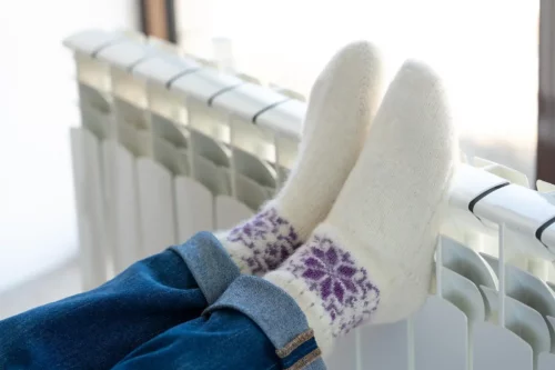 Person sætter sine fødder med varme sokker op på en radiator