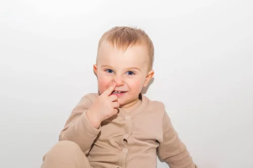 Lille dreng peger på sin næse som eksempel på at lære børn om kropsdele