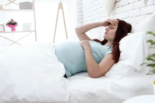 Træt gravid kvinde i seng