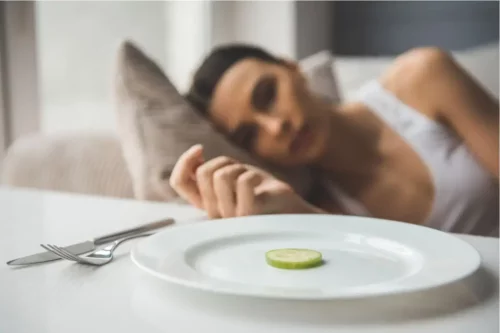 Kvinde med en enkelt skive agurk på sin tallerken repræsenterer bulimi og anoreksi