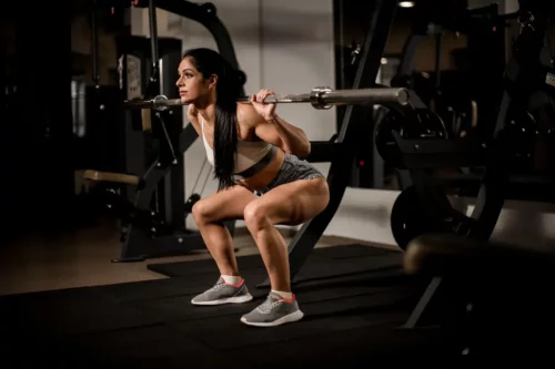 Kvinde laver squat med vægte