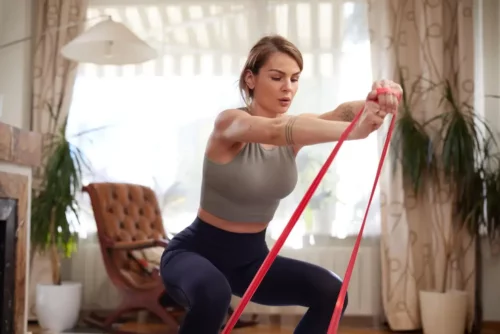 Kvinde laver squat med bånd i en træningsrutine til ballerne