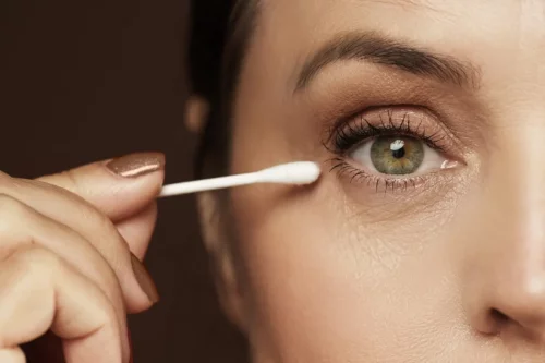 Kvinde lægger makeup på hængende øjenlåg