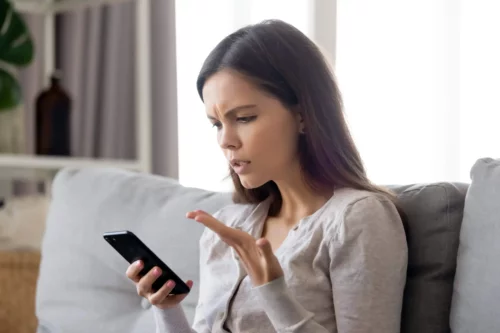 Frustreret kvinde med telefon oplever misbrug på WhatsApp
