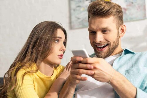 Mand med telefon og en frustreret kvinde ved sin side