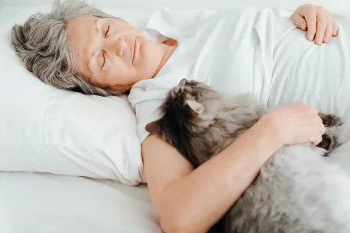 Person viser, hvordan man kan sove sammen med en kat