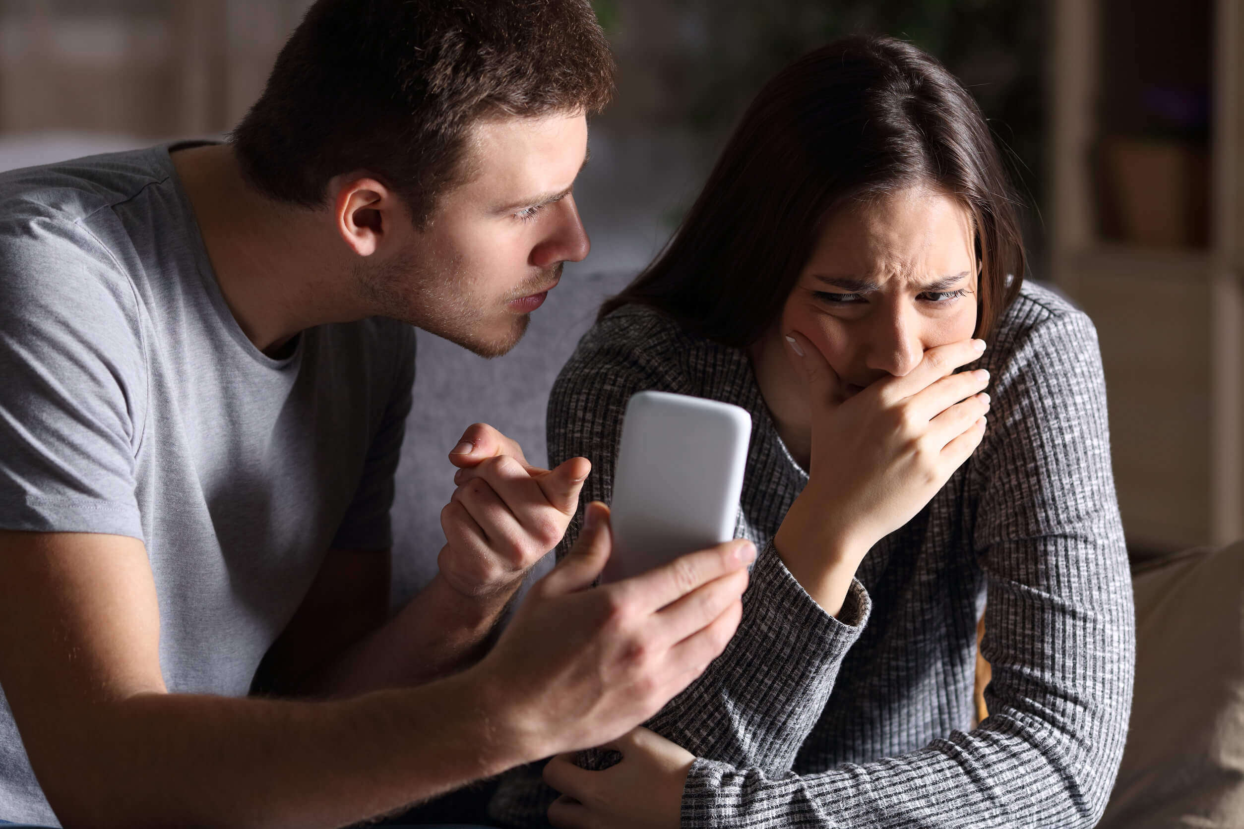 Vred partner med telefon i hånden illustrerer misbrug på WhatsApp