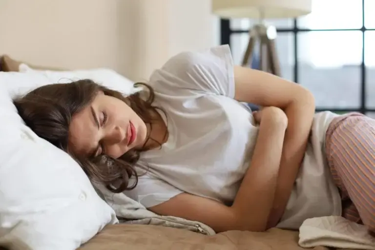 Kvinde med mavepine ligger i seng