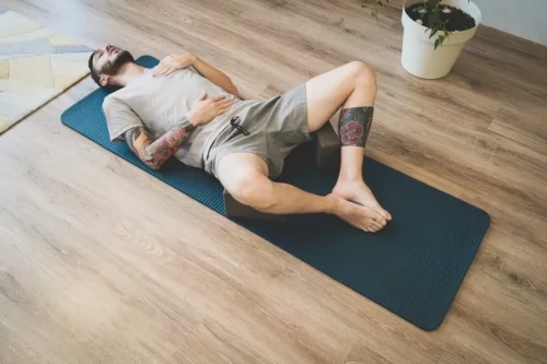 Mand ligger på en yogamåtte